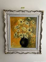Photo shows the full vintage framed floral painting with yellow flowers in a black vase against a warm yellow background.