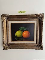 Oil painting of lemon and orange in a decorative golden frame, showing size as 16 by 14 inches.