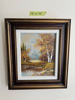 Photo of a framed vintage landscape painting with trees, water, and hills, measuring 13x15 inches.