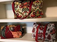 Three colorful fabric totes displayed on white shelves in a row.
