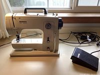 Full side view of the Bernina model 802 sewing machine plugged in with the power cord visible, includes black foot pedal.