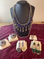 Main photo showing lapis necklace on bust with earrings and other silver jewelry items displayed on stands.