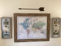 Front view of entire set showing large framed map in center, two framed postcard displays on each side, and metal arrow mounted above.