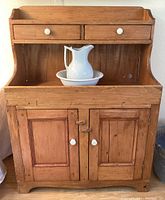 Front view of wood dry sink cabinet with two drawers and porcelain basin and pitcher set