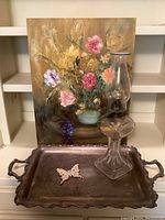 Full lot view showing floral painting, oil lamp, silver tray with butterfly
