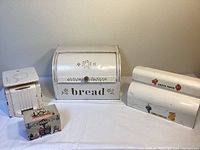 Full view of four vintage painted metal kitchen items: bread box, recipe box, kitchen scale, waxed paper holder.
