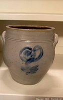 Front view of gray stoneware crock with cobalt blue flower design and side handles.