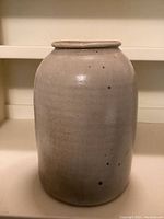 Front view of vintage stoneware crock showing shape, surface glaze and speckled finish.