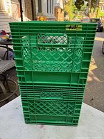 Photo showing two stacked green plastic milk crates branded Neilson in good condition.