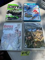 Photo showing four Wii game cases laid out on flat surface: Dirt 2, Mario & Sonic at the Olympic Winter Games, Rapala Pro Bass Fishing, Call of Duty.