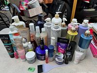 Lot of various shampoos, conditioners, hand creams, jars and tubes mostly full, arranged on floor with labels visible