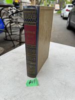 Photo of the antique book standing on a white table showing spine with decorative patterns and title label.