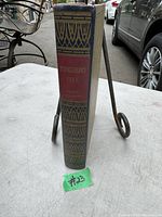 Photo of the spine of the antique book showing decorative gold stamps with a red label having the title and author's name.