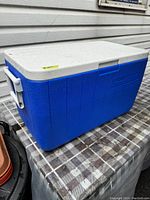 Blue and white Coleman cooler closed, showing exterior with side handles and lid.