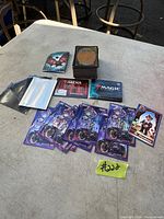 Top view of the lot showing stack of Magic the Gathering cards, card sleeves, and promotional materials on a table.