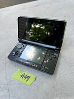 Black Nintendo 3DS handheld console open showing dual screens, control buttons, and circle pad.