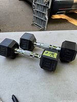 Pair of black rubber hexagonal dumbbells each with embossed '10' on ends. Chrome handles with knurled anti-slip grips. Placed on flat surface, in very good condition.