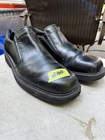 Pair of black Rockport men's leather slip-on shoes on a surface with a small yellow sticker showing #160