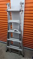 Folded articulated aluminum ladder made by Mastercraft, showing multiple sections and non-slip feet.