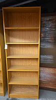 Photo of the first light oak color wood bookshelf showing multiple adjustable shelves and screw hole damage.