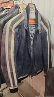 Front and side view of dark blue Danier leather jacket with white stripes on sleeves