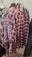 Three men's plaid dress shirts from Van Heusen and Tommy Hilfiger on hangers showing front and collar details