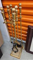 Full view of brass fireplace tool set including stand and all tools, showing the design and overall appearance.