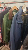 Hanging men's coats showing a green L.L.Bean jacket with brown collar and a blue coat.