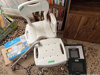 Aquasense folding bath seat, stainless steel grab bar, and Colby digital scale box with scale on carpet next to seat