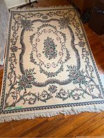 Full view of the floral area rug showing design and fringe edges.