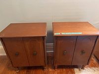 Front view of the two matching wooden bedside tables showing double doors and carved legs.