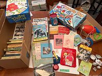 Overview of the lot showing Zingo and Moustrap board games, many children's books, small stamp book, and some small toys including a toy egg and tea set.