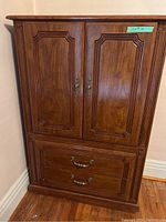 Full front view of dresser showing two closed cabinet doors on top and two closed drawers below, with wood finish and decorative handles.