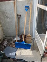 Full lot with shovel, rake, broom, bucket, blue plastic snow shovel, rubber boot trays leaning against wall