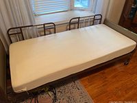 Assembled hospital bed with beige-fitted extra-thick mattress and side rails visible