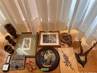 Wide view of the lot with Norman Rockwell plated display, framed art prints, wooden vases, friendship plaque, wooden shoes, and mounted antlers visible