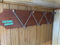 Front view of the wooden backboard with attached metal hooks featuring wooden ball ends, showing overall length and design.
