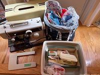 Full view of the Calandra sewing machine, carrying case, white accessories, and bag filled with knitting/crochet items and sewing tools.