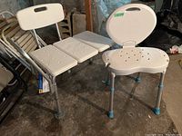Two white plastic shower chairs with adjustable metal legs and drainage holes, one with backrest and one without, shown on concrete floor.