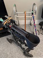 Foldable walkers and canes arranged on carpeted floor showing walker seats and cane handles.