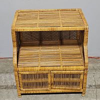 Front angled view showing the woven wicker and rattan cabinet with its structure and doors.