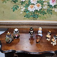 All seven fall-themed figurines including two owls, pilgrim couple, two Native American figurines, and turkey shown on wooden table