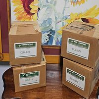 Four cardboard boxes on a wooden table, each labeled with Kim Lighting brand and catalog number ELN-87A.