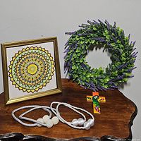 Overall view of all items including wreath, framed art, tiebacks, and painted parrot cross on wooden surface.
