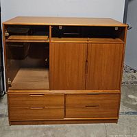 Front view of closed mid-century teak wood wall unit showing cabinet doors and drawers