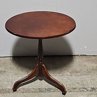 Full view of round mahogany pedestal table showing circular tabletop and tripod-legged base.