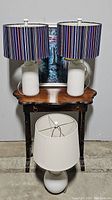 Full view of the set showing two striped shade lamps on wooden side table and smaller white lamp on floor