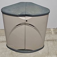 Front view of green and tan Rubbermaid plastic yard box with closed double doors and slightly worn green lid.