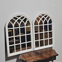 Photo of two rustic arched window mirrors side by side showing full design and proportional size on wooden table.
