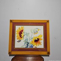 Front view of the framed sunflower watercolor painting, showing the carved sunflower details on the wood frame corners and the reddish-brown mat border.
